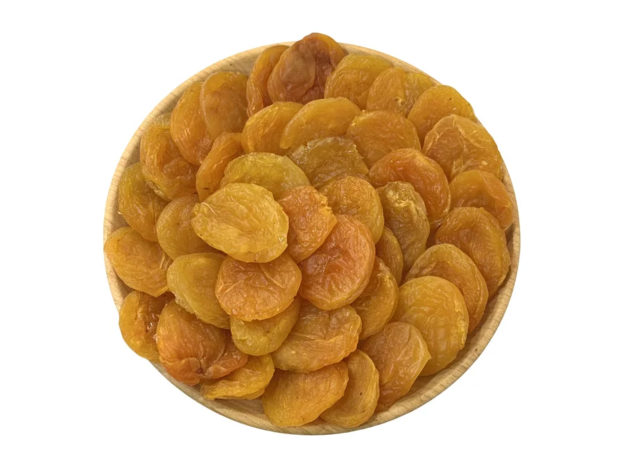 A wooden plate heaped with Armenian dried apricots, deep amber to orange, seen from directly above