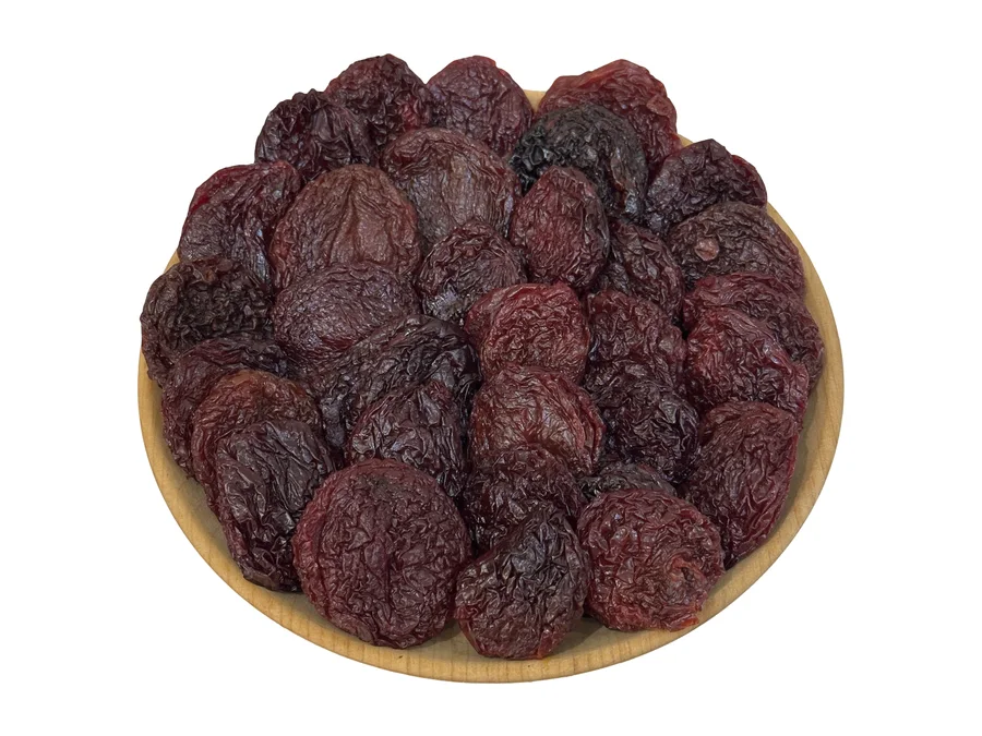 A wooden plate of Armenian dried alycha halves, deep reddish-brown, seen from above
