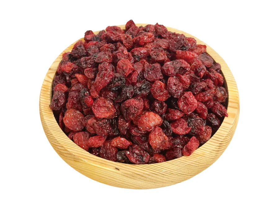 A wooden plate heaped with Armenian soft-dried red cherries, deep glossy red to near-black, seen from above
