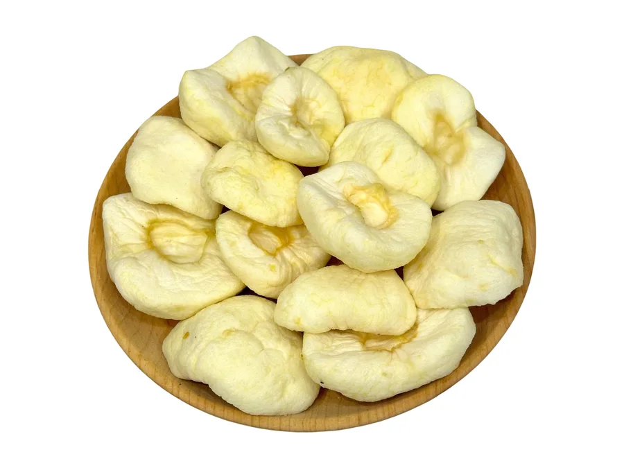 A wooden plate of Armenian dried apple pieces, pale cream with honey-coloured centres, seen from above